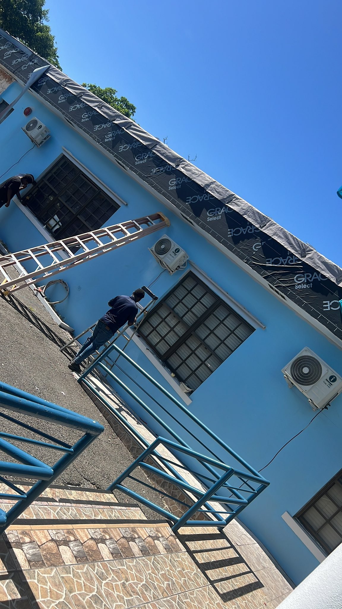 Technicians installing AC units on building exterior